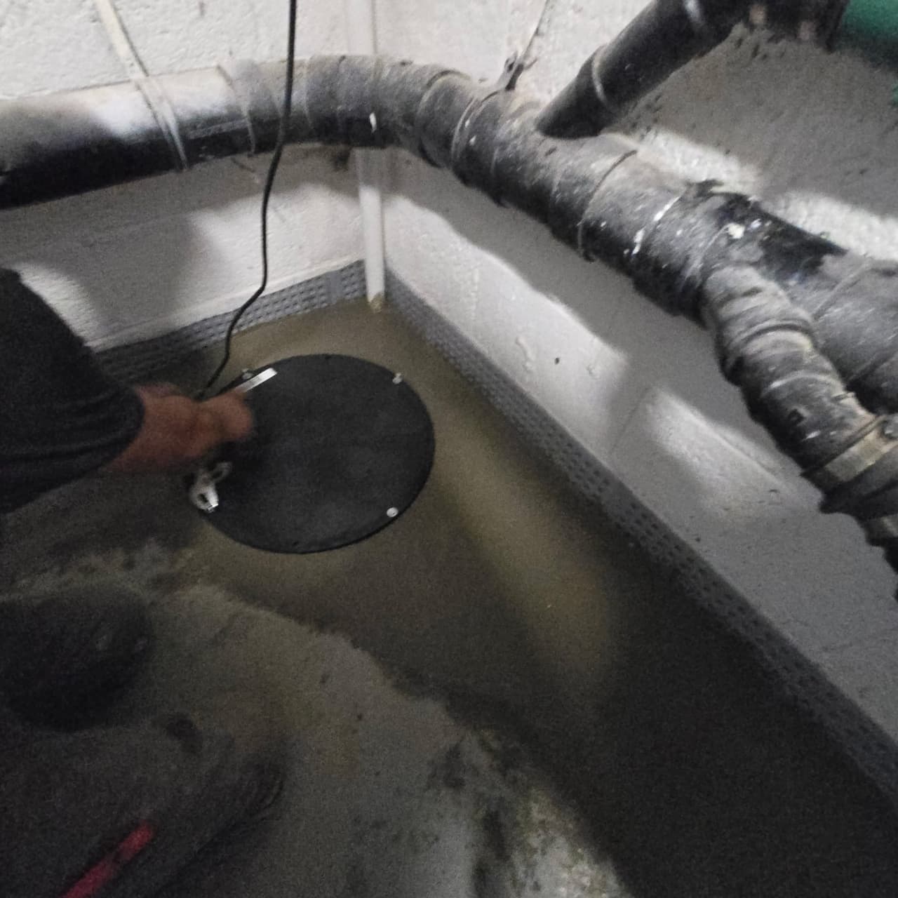 Sump basin cover and discharge pipe detail in a basement
